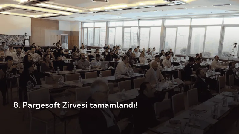 Bir konferans salonunda masalarda oturan çok sayıda katılımcı ekrandaki sunumu izliyor.
