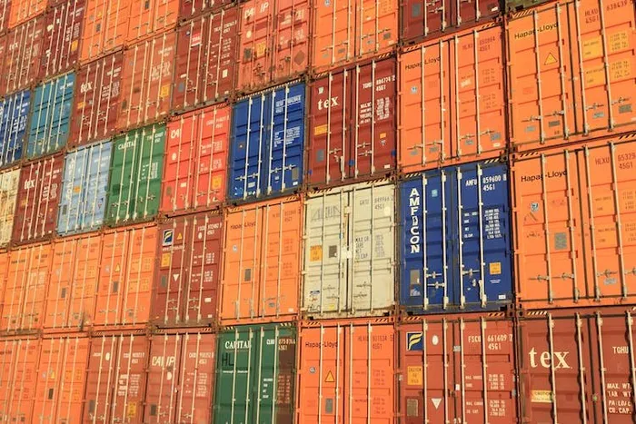 Üst üste istiflenmiş çok renkli deniz konteynerleri; bazılarında Hapag-Lloyd yazısı okunuyor.