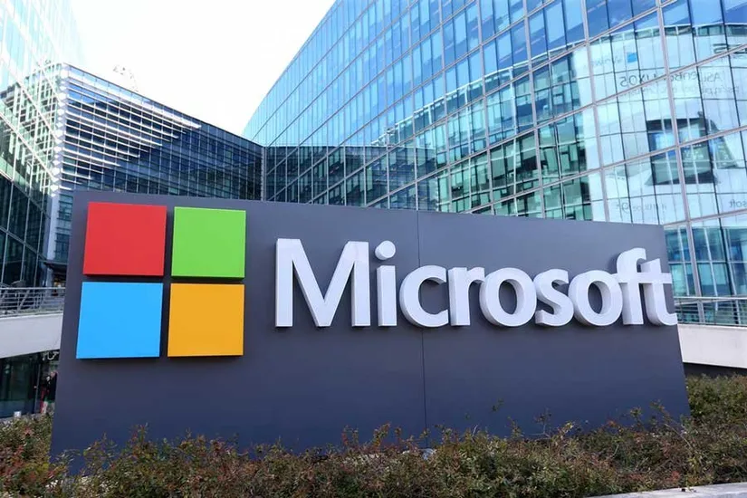 Microsoft logosu, cam cepheli bir ofis binasının önündeki tabelada