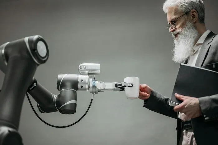 Bir robot kolu, takım elbiseli yaşlı bir adama kahve fincanı uzatıyor