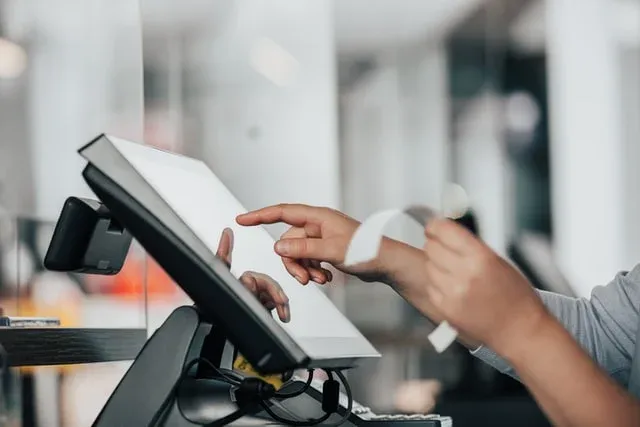 Kasiyerin dokunmatik POS terminalinde işlem yaparken adisyon fişini tutması