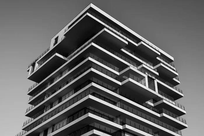 Balkonlu, modern bir apartman binasının siyah beyaz çekilmiş dış cephe fotoğrafı.