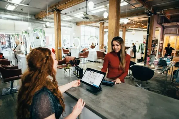 Salon receptionist using hospitality point-of-sale software on a tablet
