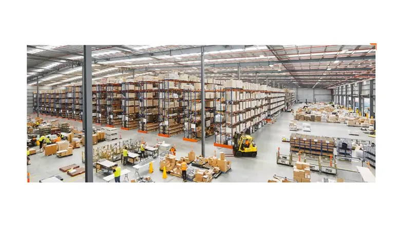 Düzenli raflar, forklift ve çalışanlarla işleyen organize bir depo iç mekânı