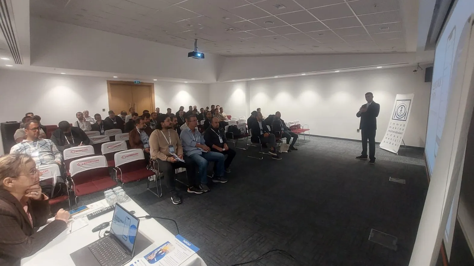 TMMOB Makina Mühendisleri Odası Denizli Şubesi salonunda sunum yapan bir konuşmacı ve dinleyiciler