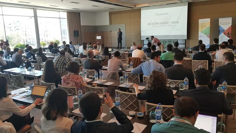 Ekranda 'Müşteri Günü - 2019' sunumu gösterilirken masalarda oturan katılımcılar