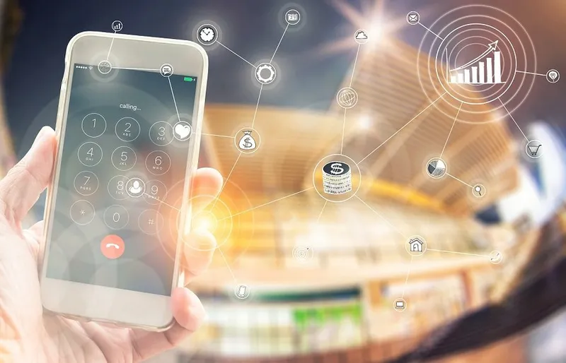 Bir elin tuttuğu telefon ekranından alışveriş merkezi görüntüsüne uzanan ikon bağlantıları