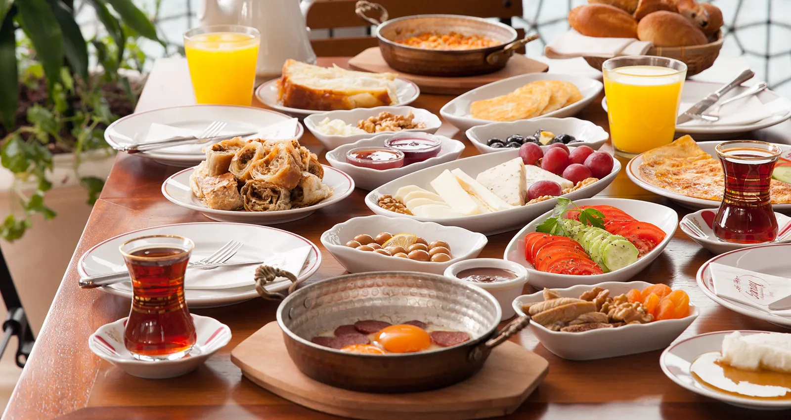 Saray Muhallebicisi'nde çay, portakal suyu, peynir tabağı ve sucuklu yumurtalı zengin bir kahvaltı sofrası
