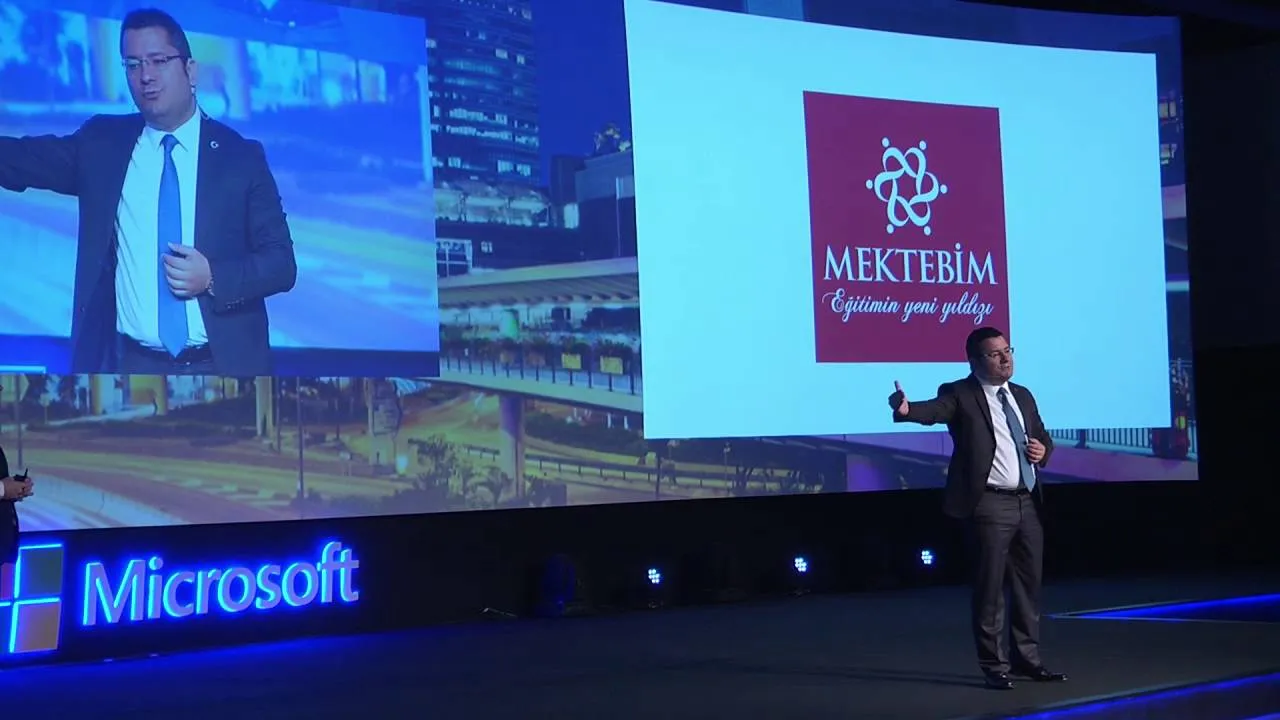 Microsoft sahnesinde MEKTEBİM logosunun yansıtıldığı ekran önünde konuşan sunucu